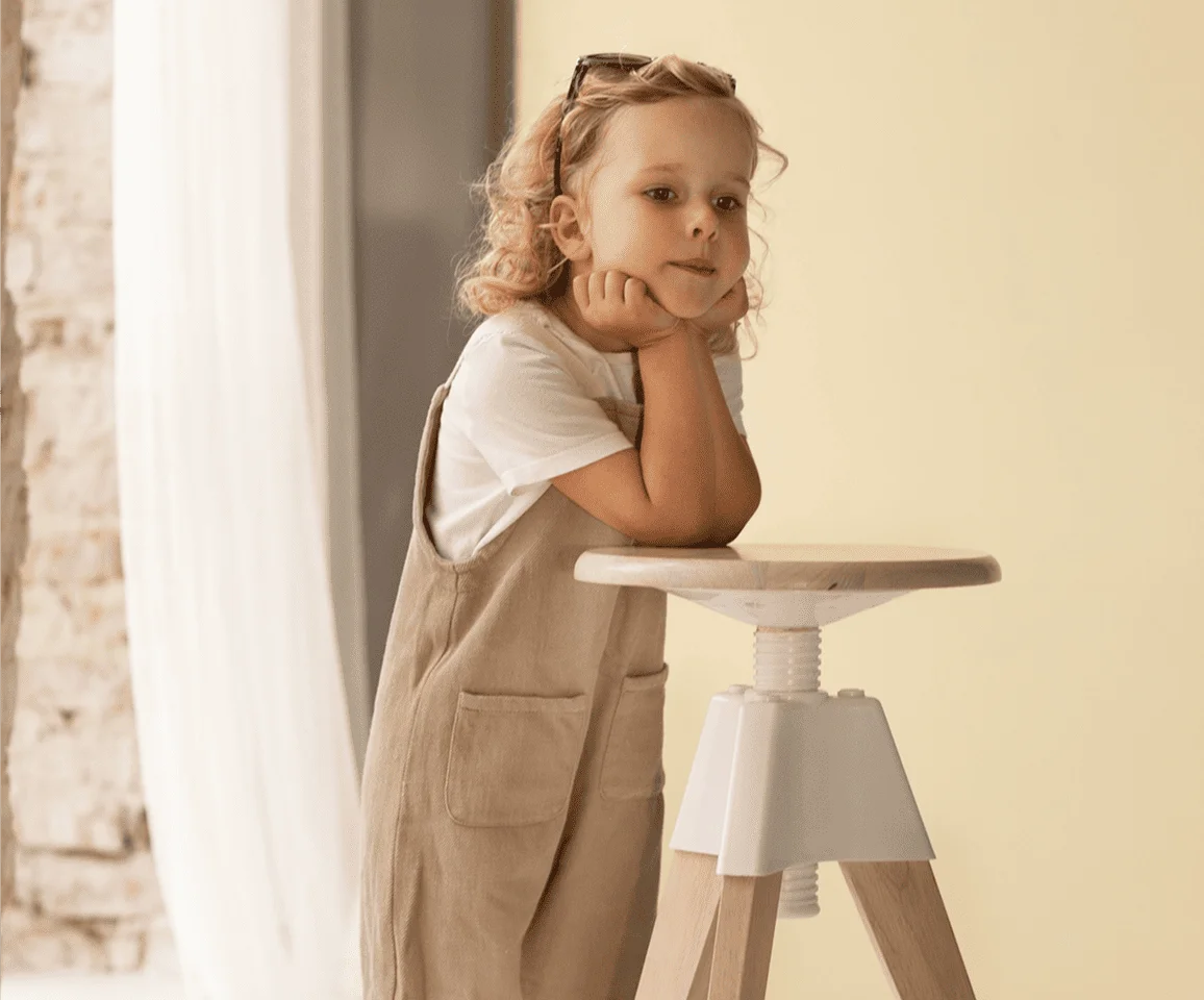 Little girl in a brown pinafore dress twirling playfully